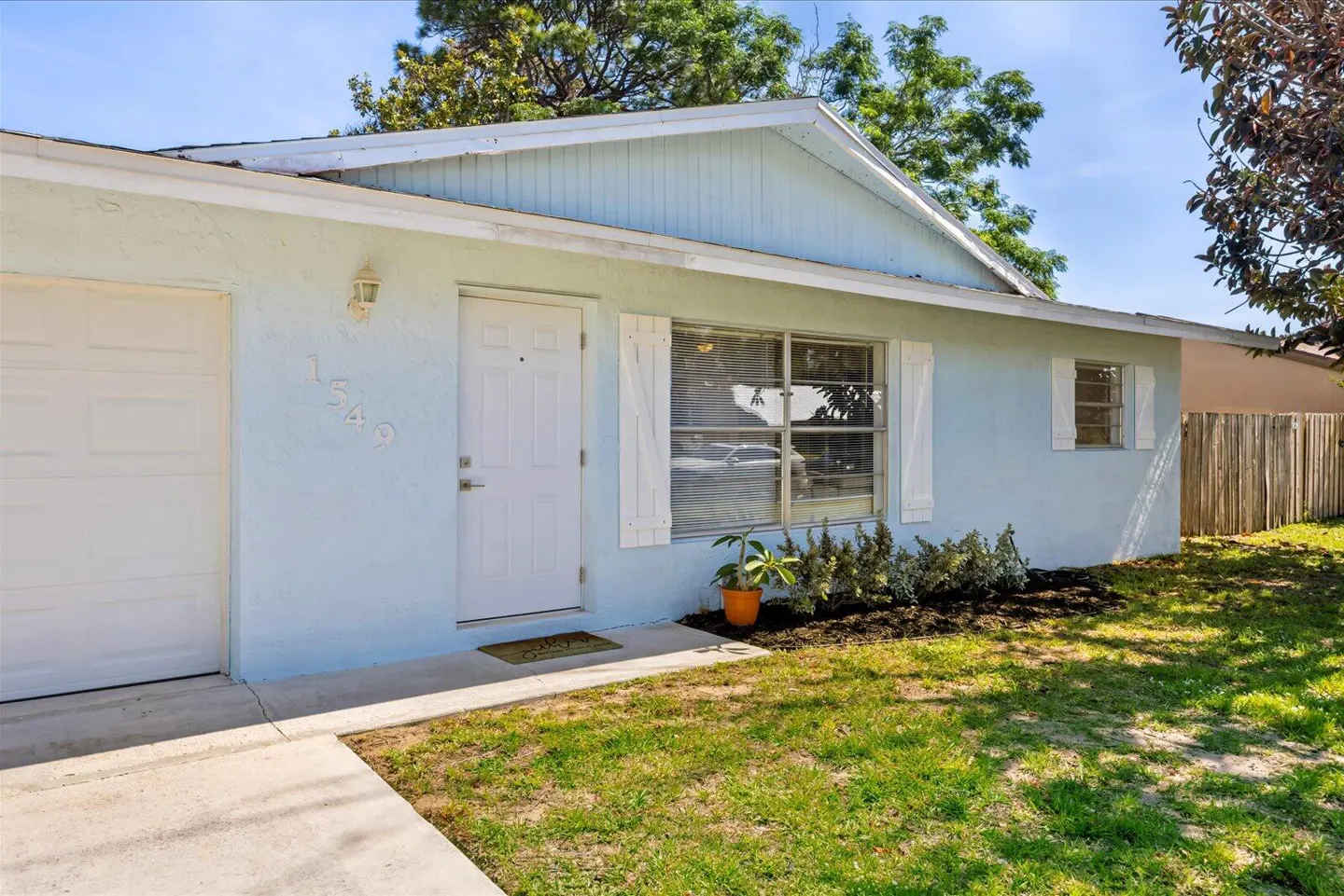 Exterior of a light blue single-story home with white trim, a white front door, and a green lawn.