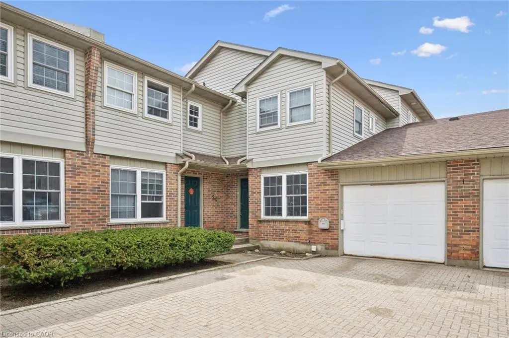 Exterior view of a two-story townhouse with brick and siding, a white garage door, and a green front door.