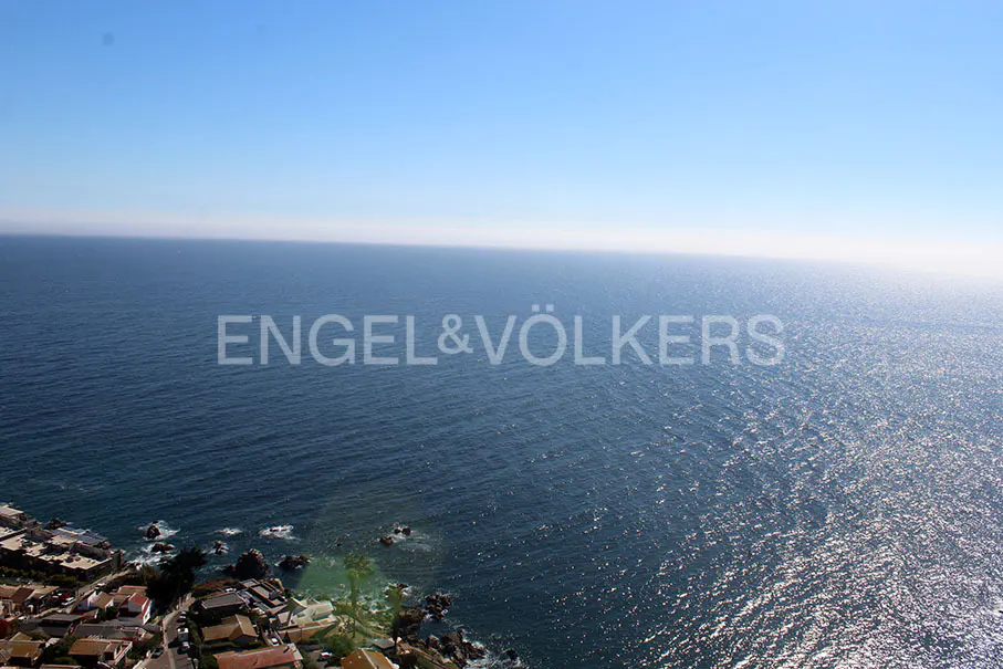 Ocean view from a coastal town, blue sky above, Engel & Völkers logo.
