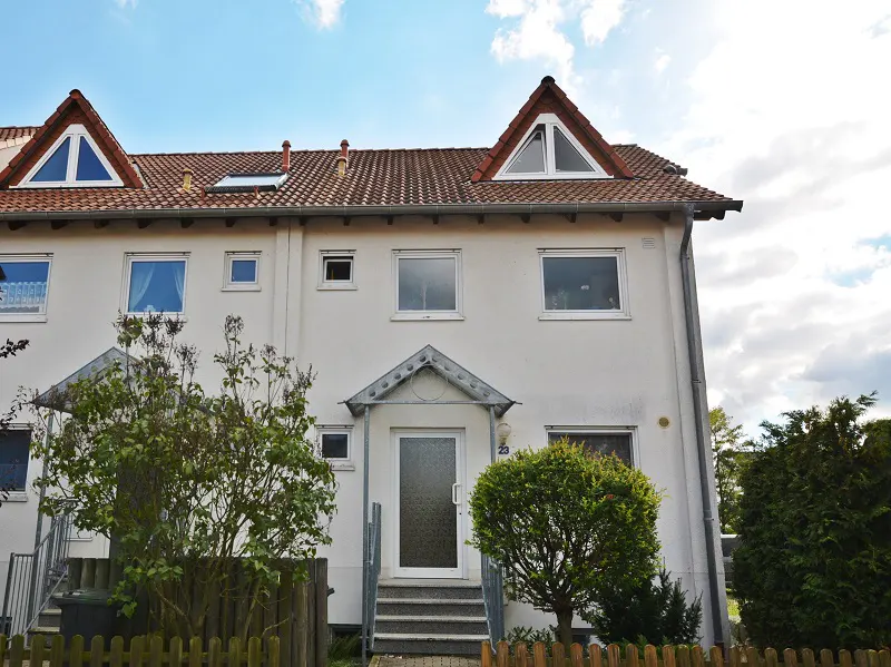 Exterior view of a white, two-story townhouse with a red-tiled roof and a small front yard.