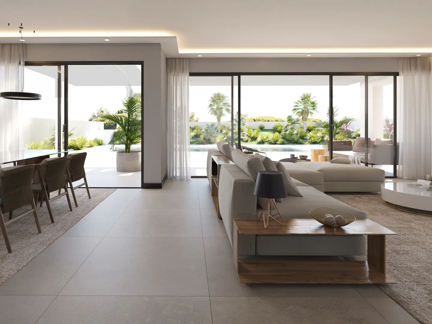 Bright, modern living room with a beige sectional sofa, wood table, and dining set. Large windows offer views of a lush green yard and pool.