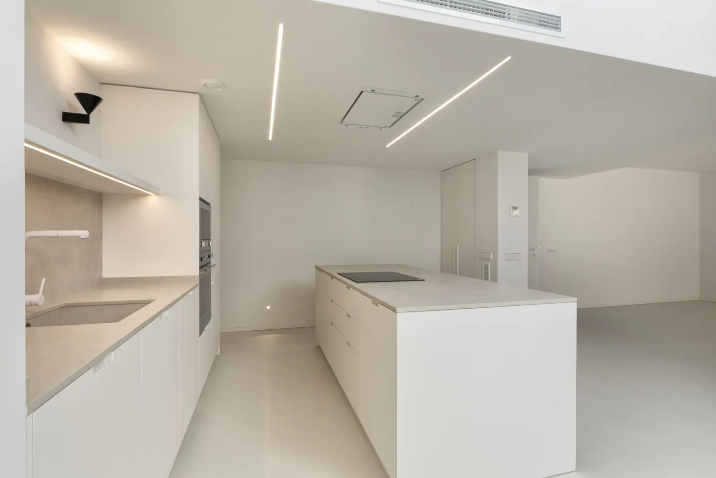 Bright, modern kitchen with white cabinets, countertops, and island. Linear lighting fixtures on the ceiling. Open floor plan.