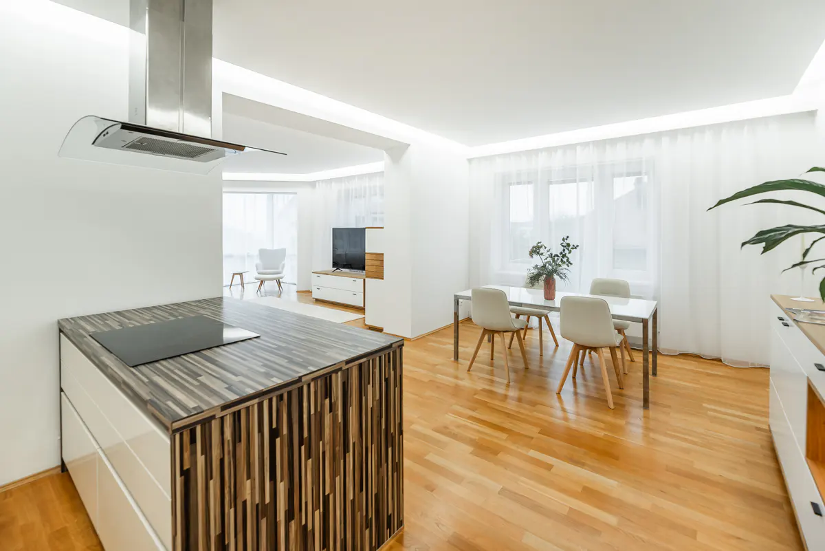 Bright, modern open-concept living space with wood floors, white walls, kitchen island, dining table, and living room.