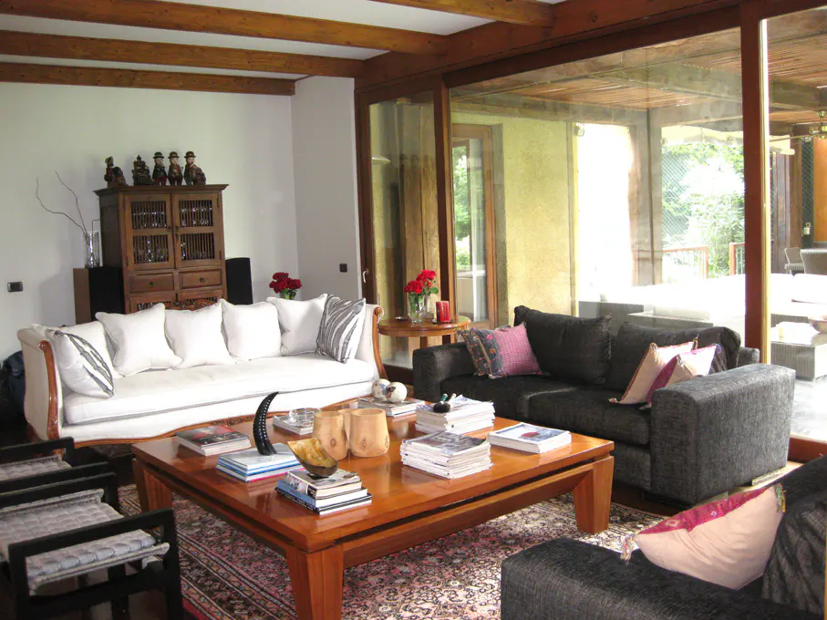 Living room with white sofa, dark gray sofa, and wooden coffee table with books. Large windows overlook a patio.