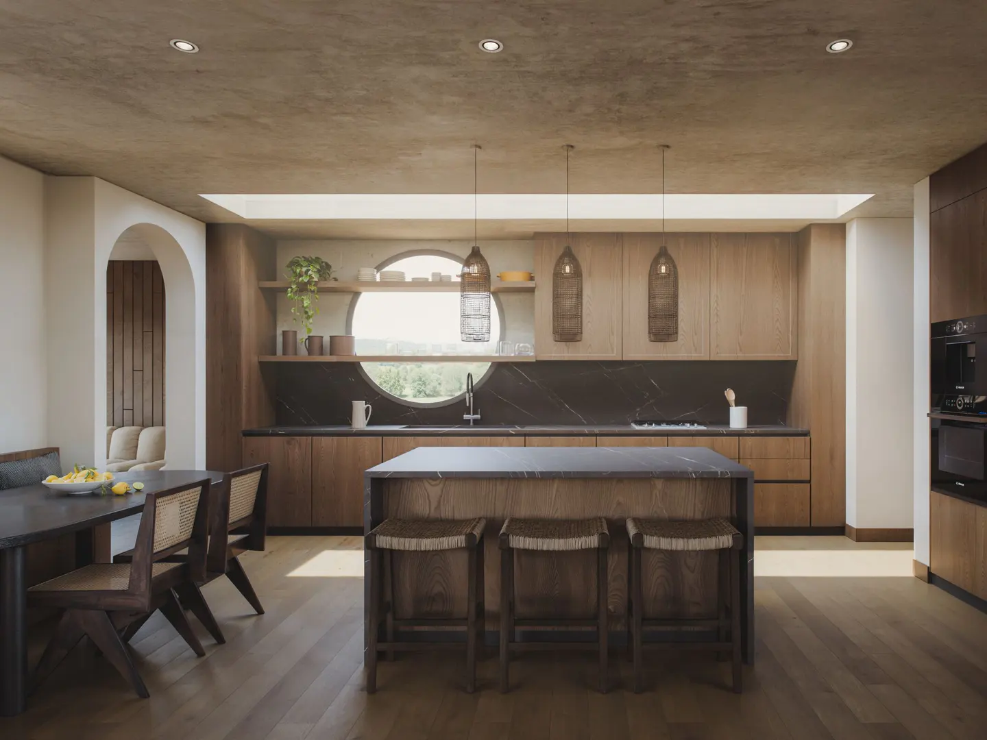 A modern kitchen with wood cabinets, a black countertop, and a central island with three stools. A round window is above the sink.