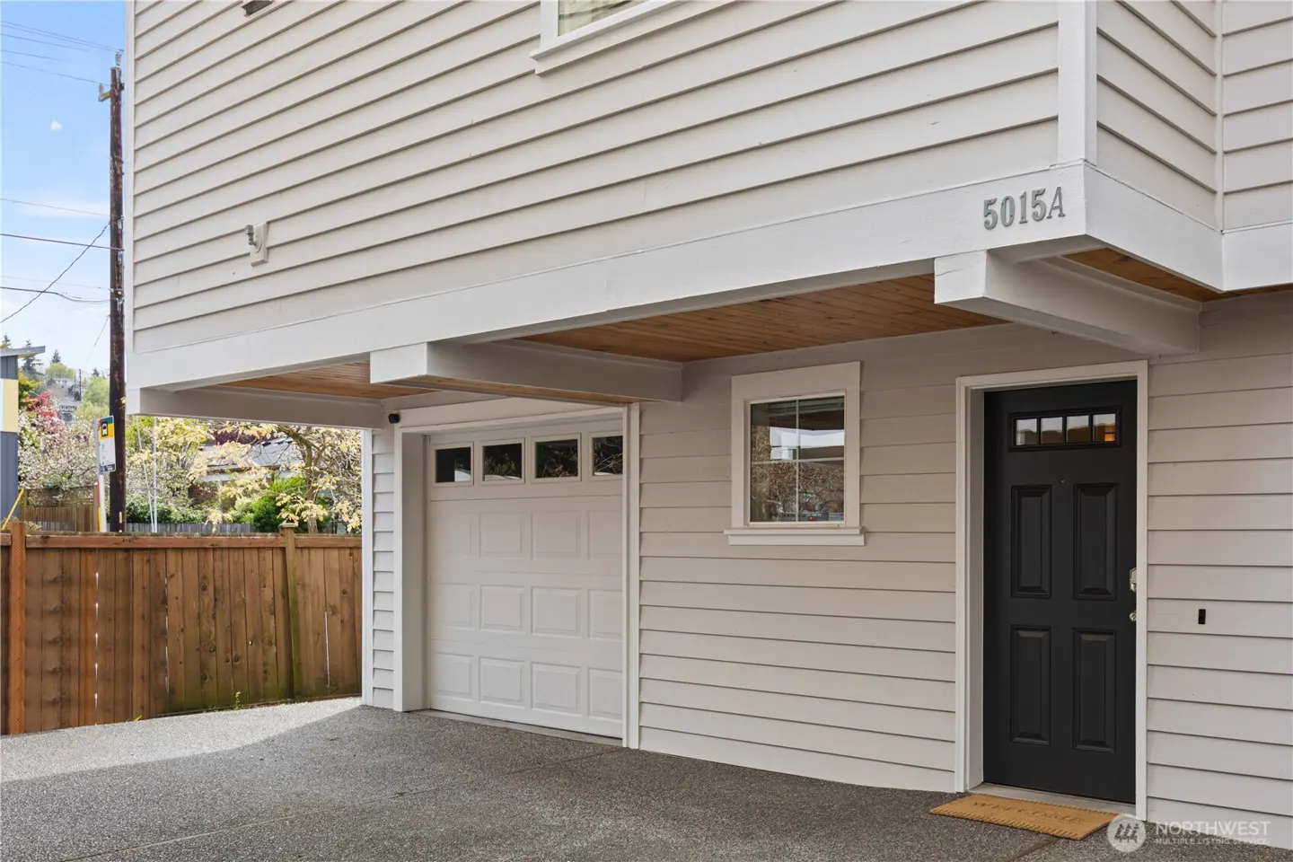 Exterior view of a light gray house with a black front door, white garage door, and the address "5015A" above the door.