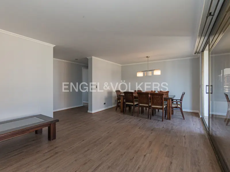 A dining room with a wooden table and chairs, light gray walls, and a wooden floor.
