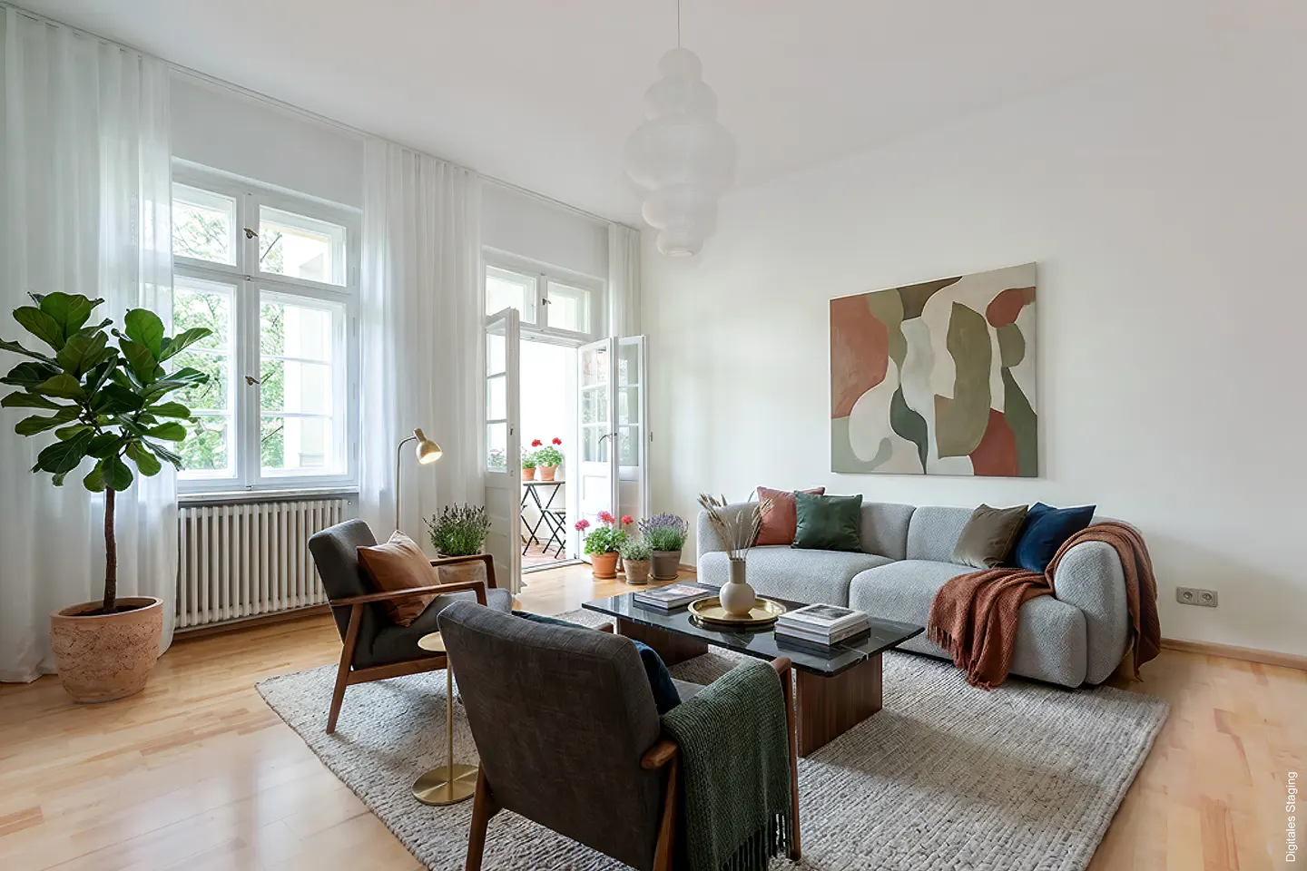 Bright living room with a grey sofa, two armchairs, a coffee table, abstract wall art, and a balcony with potted flowers.