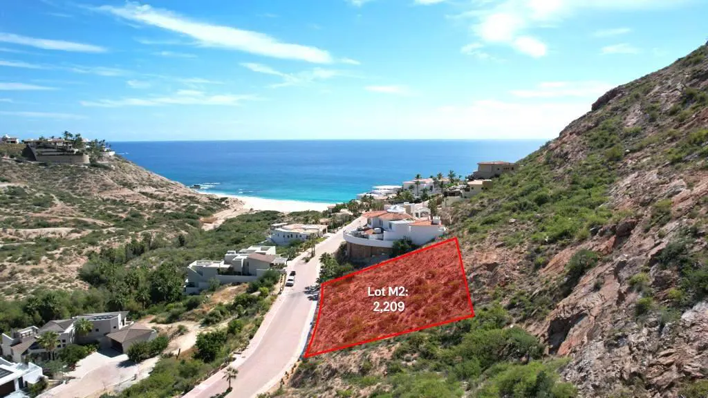 Aerial view of Lot M2, 2,209 sq ft, outlined in red on a hillside near the ocean. Houses and a road are visible.