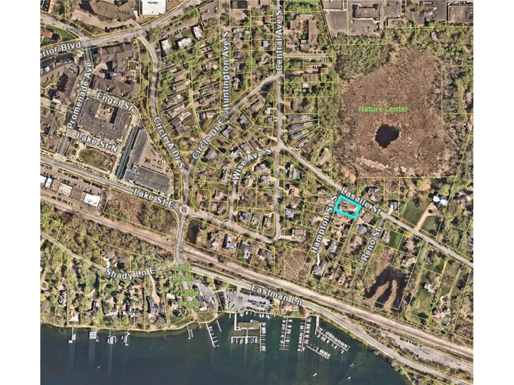 Aerial view of a residential area with a lake, marina, and nature center nearby. A property is highlighted in blue.