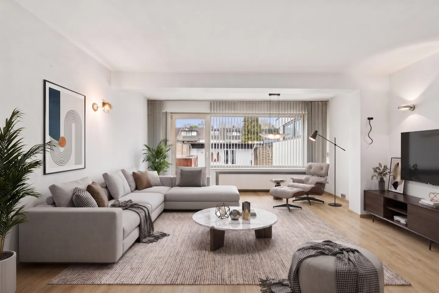 Bright living room with a gray sectional sofa, marble coffee table, and a large window with vertical blinds. A modern chair and TV stand are also visible.