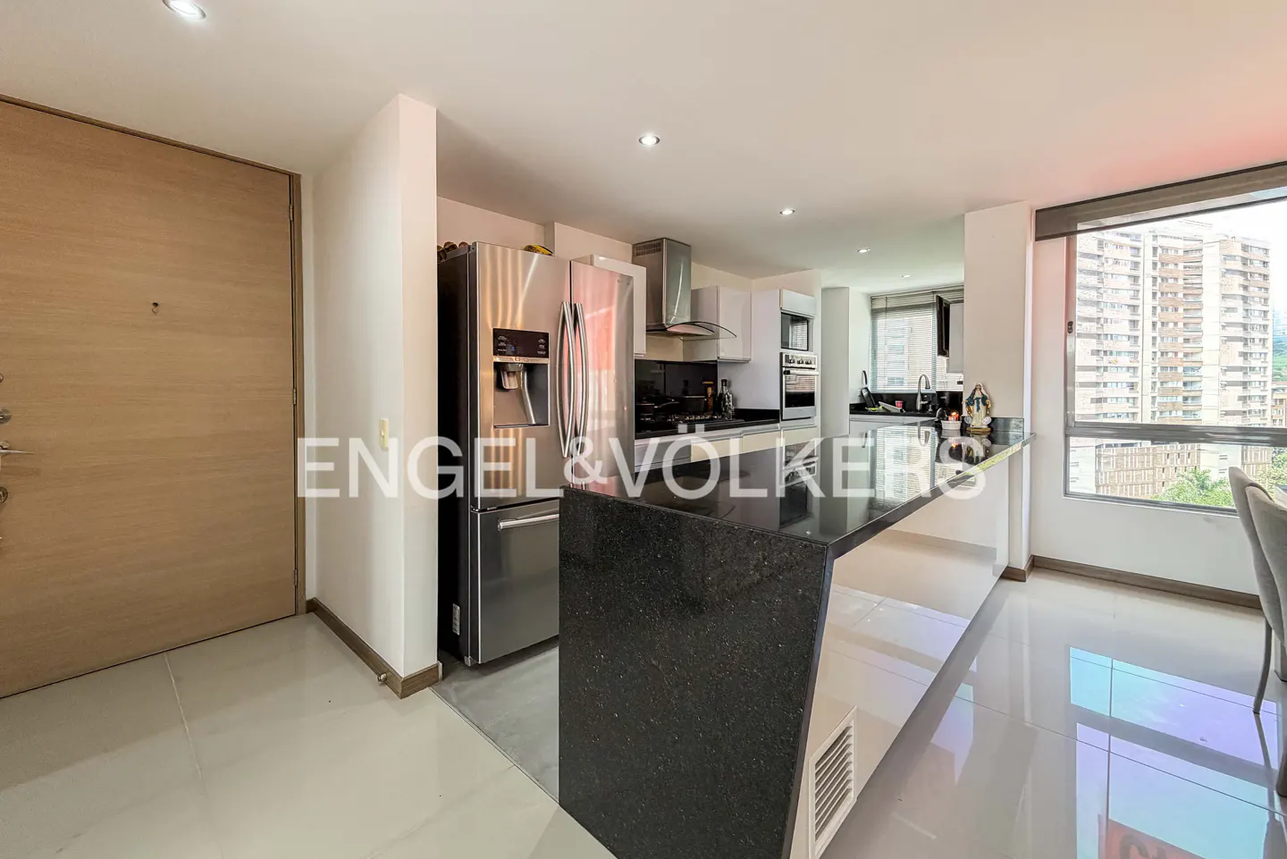 A modern kitchen with stainless steel appliances, a black granite countertop island, and a large window with a city view.
