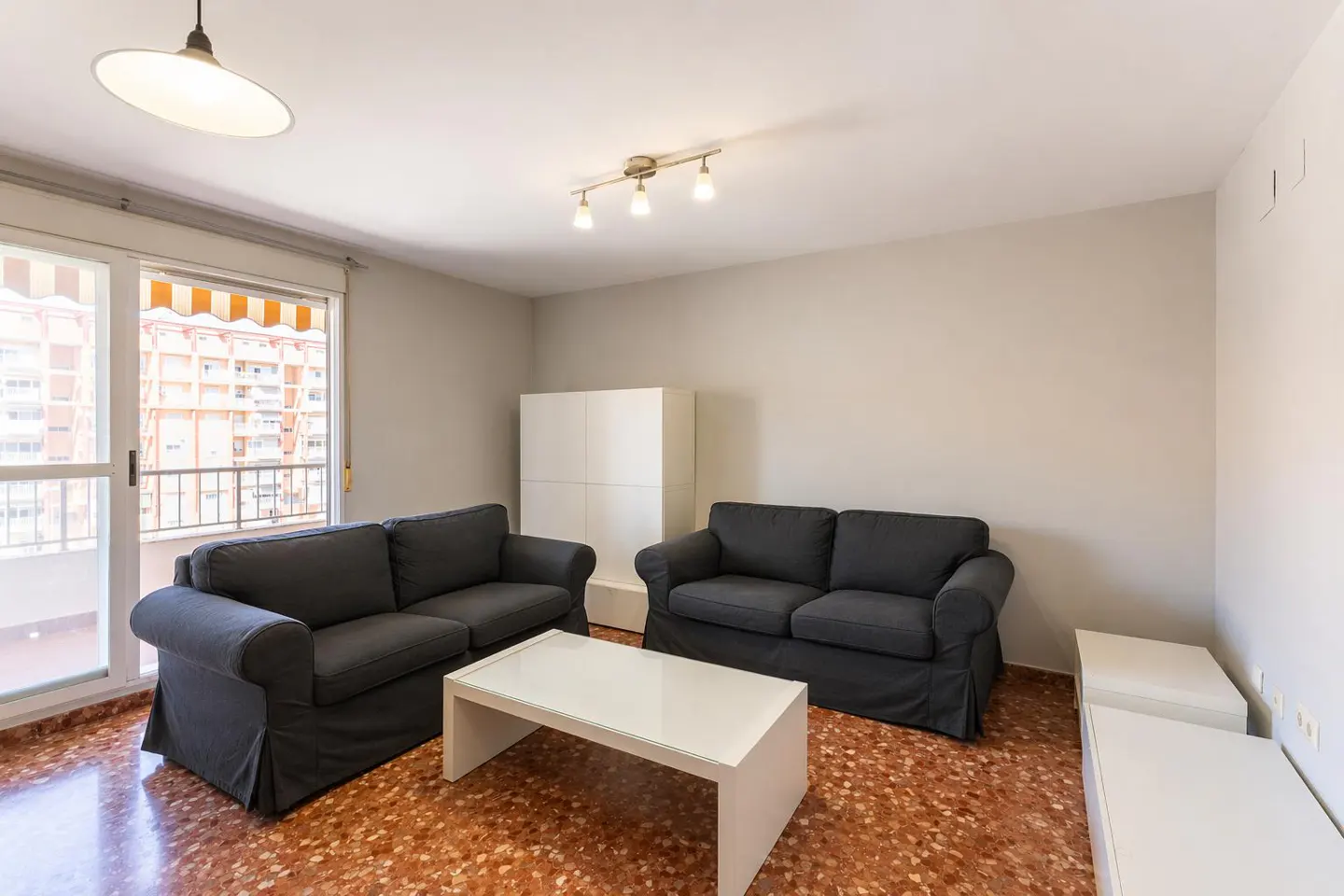 Living room with two gray sofas, a white coffee table, and a balcony with a view of a building.