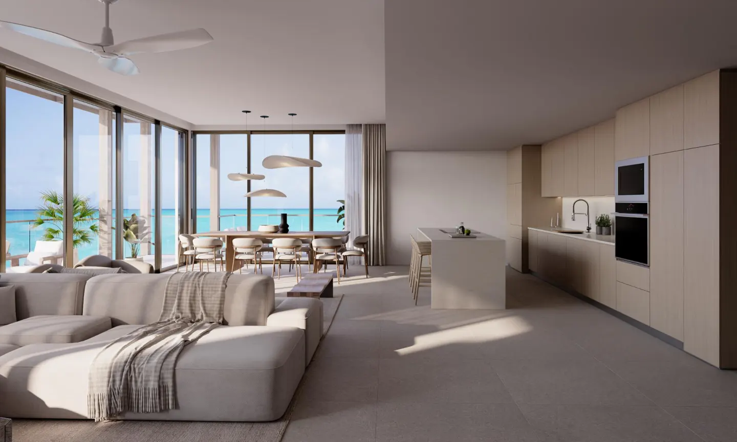 Open-concept living space with a beige sectional, dining table, kitchen island, and ocean view.