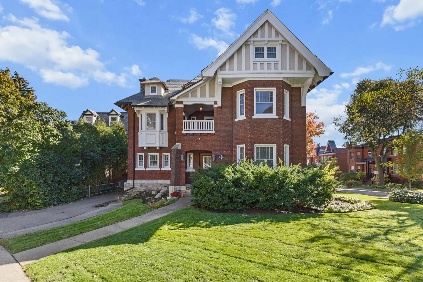 A two-story brick house with white trim and a green lawn under a blue sky.