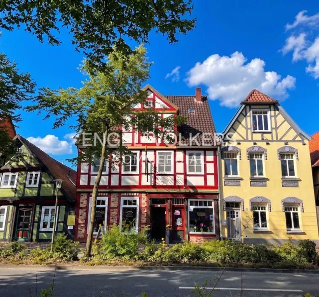 Exterior view of three colorful, half-timbered houses with white windows under a blue sky with white clouds.