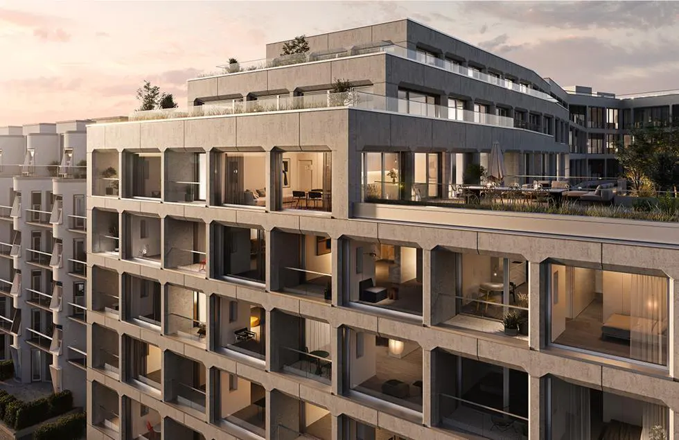 Exterior view of a modern concrete apartment building with large windows and rooftop terraces at sunset.