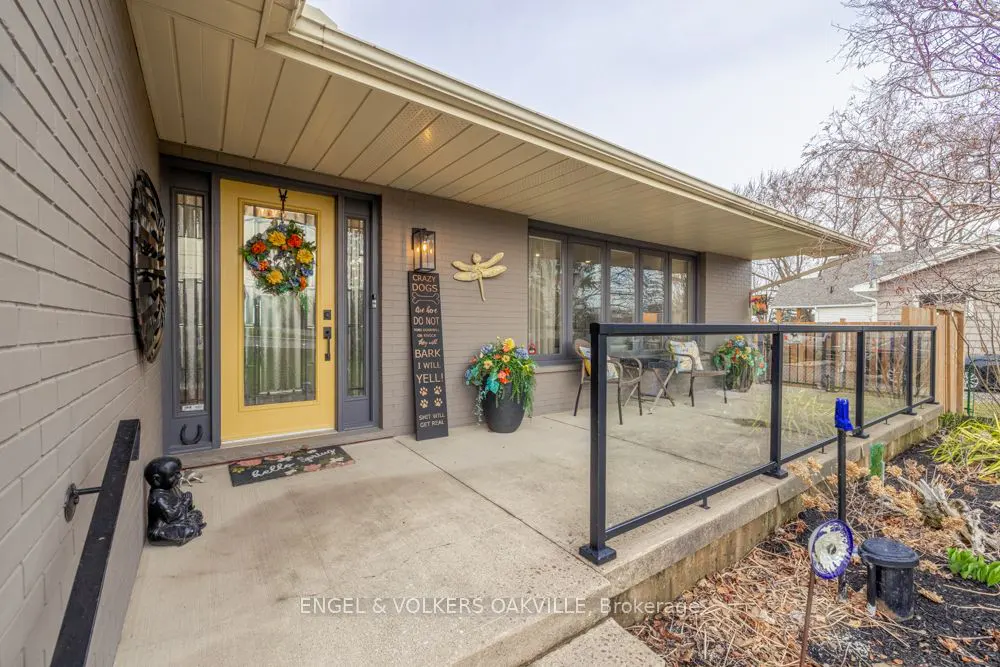 Front porch of a grey brick house with a yellow door and a glass-paneled patio.