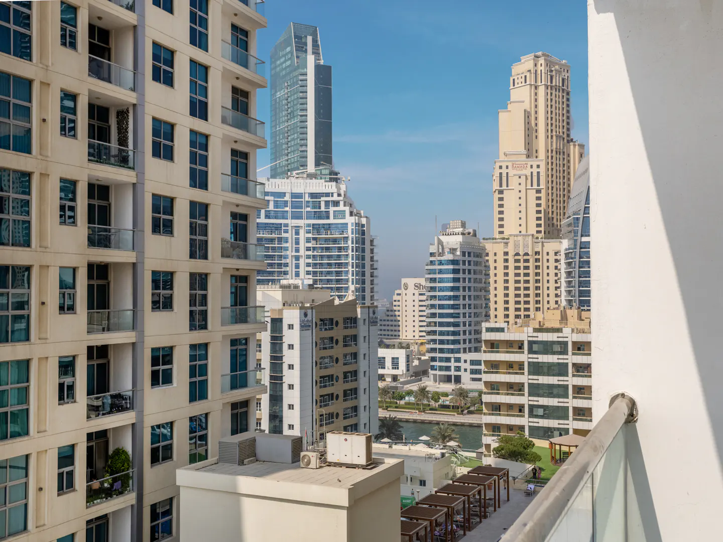 View from a balcony overlooking a city skyline with tall buildings under a blue sky.