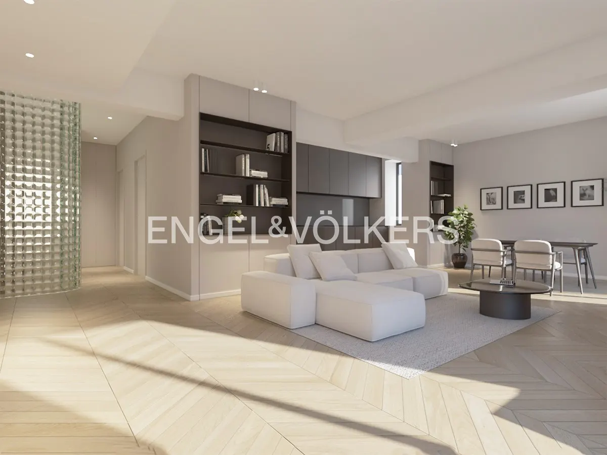 Bright, modern living room with white sectional sofa, gray rug, and wood floors. Dining table with chairs in background. Engel & Völkers logo overlay.