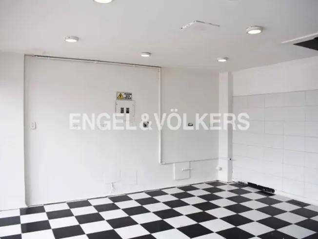 Empty room with black and white checkered floor, white walls, and recessed lighting. Engel & Völkers logo on the wall.