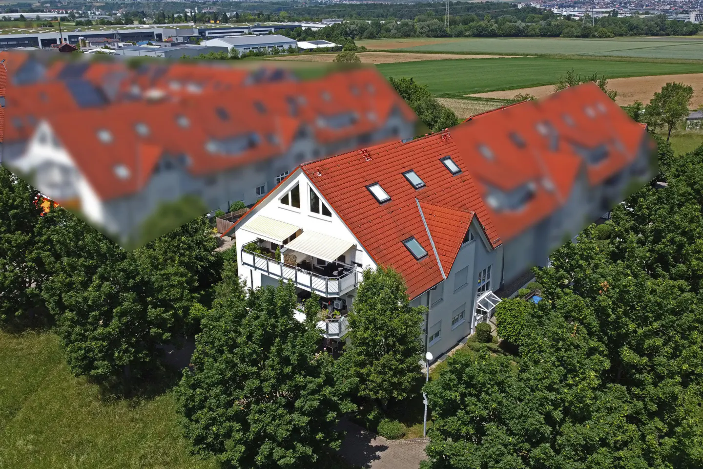 Aerial view of a white multi-story house with a red tiled roof, balcony, and surrounding trees in a rural setting.