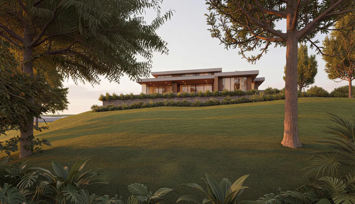 Modern house on a green hill, framed by trees. Large windows and a stone retaining wall are visible.