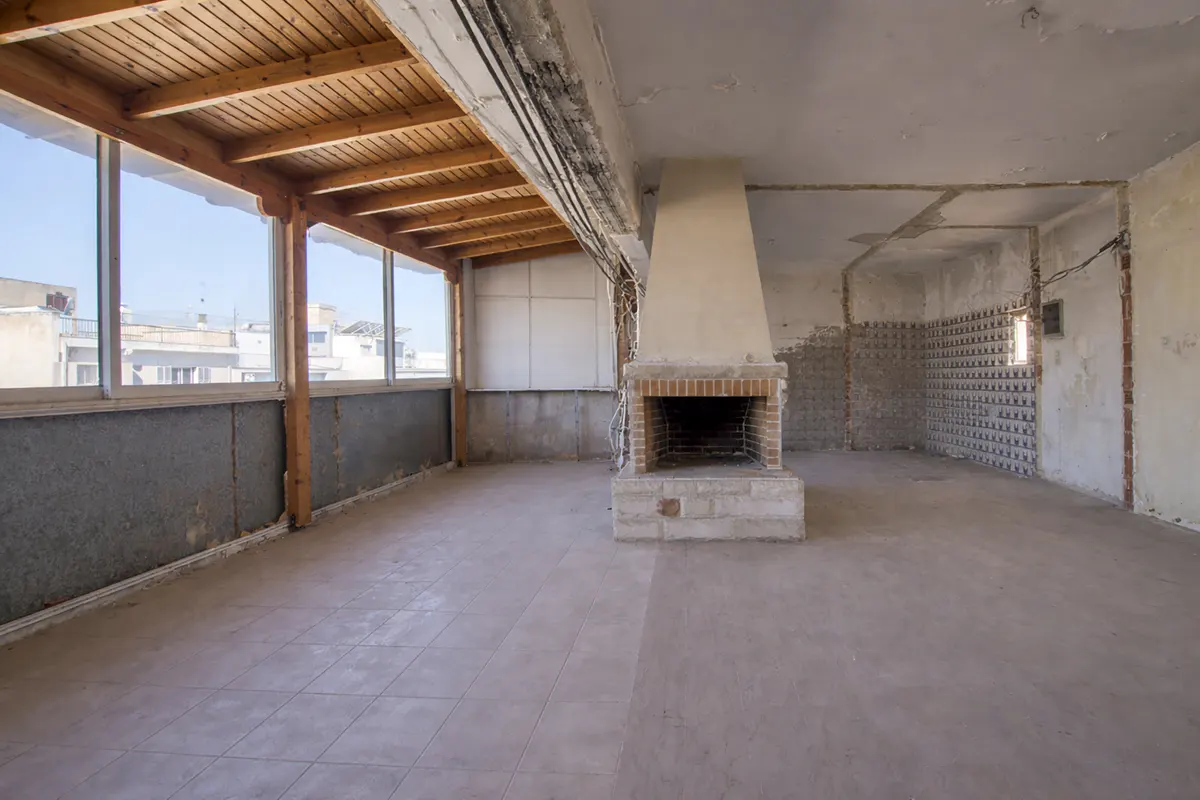 Unfinished room with a brick fireplace, tile floor, and a wood-covered patio with a view of buildings.