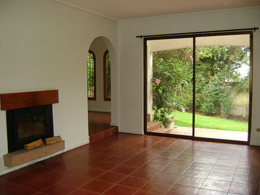 A living room with red tile floors, a fireplace, and a sliding glass door to a green backyard.