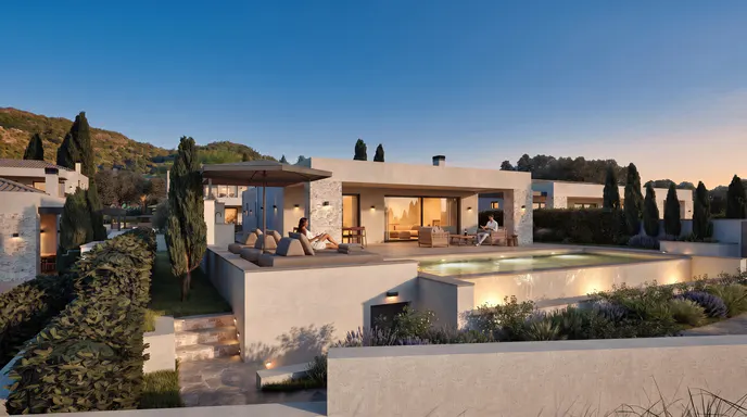 Modern villa with a pool, outdoor lounge area, and people relaxing at dusk against a backdrop of hills and trees.