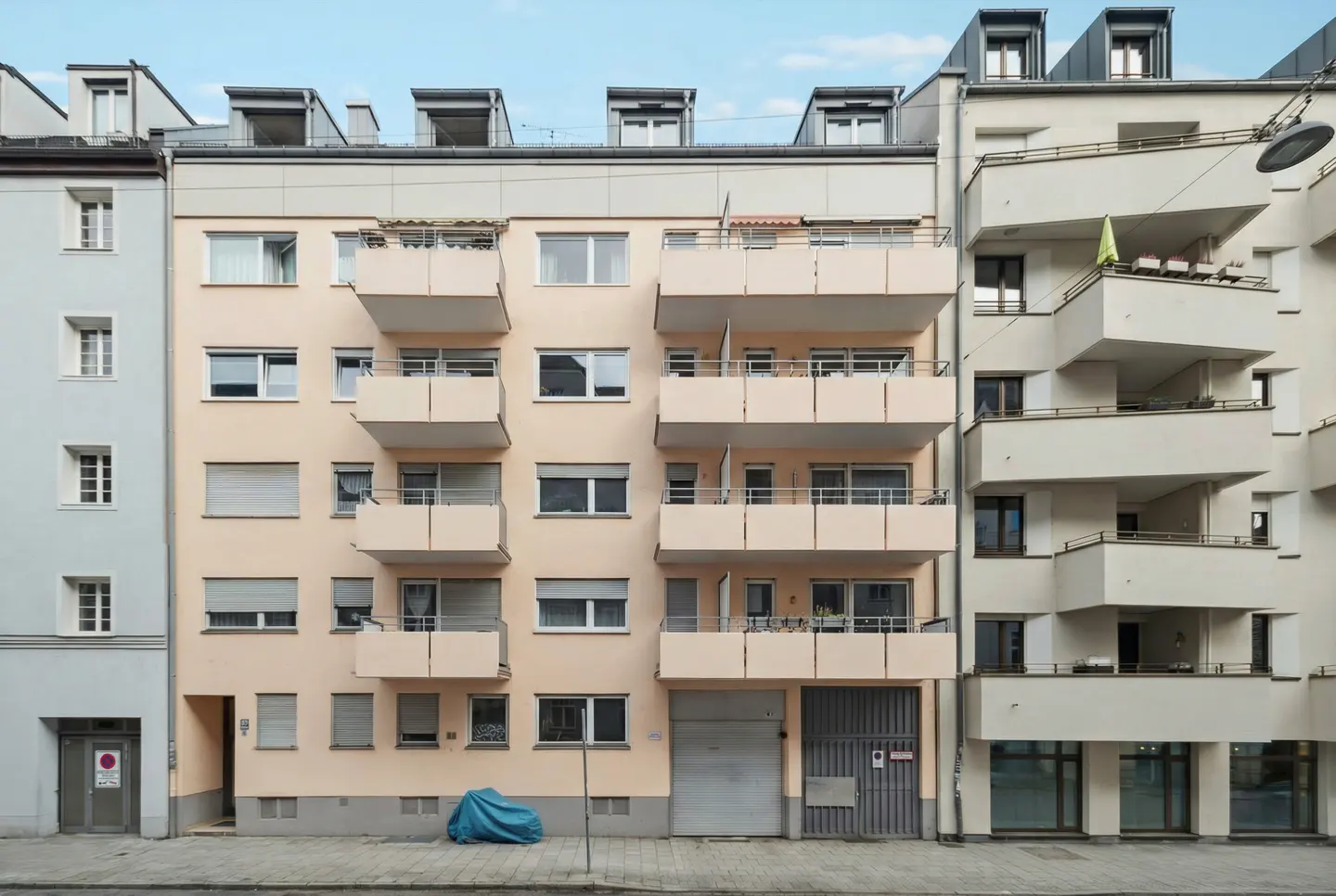A peach apartment building with balconies and a blue tarp on the ground.