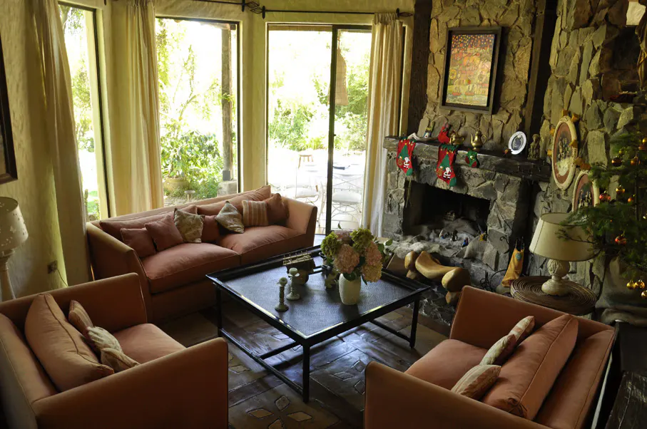 Living room with peach sofas, stone fireplace with stockings, and large windows overlooking a green yard.