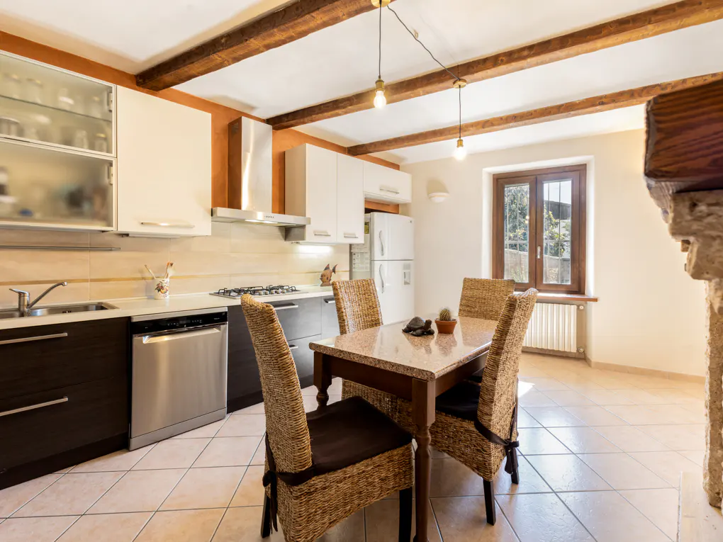 A bright kitchen with white cabinets, stainless steel appliances, and a dining table with wicker chairs.