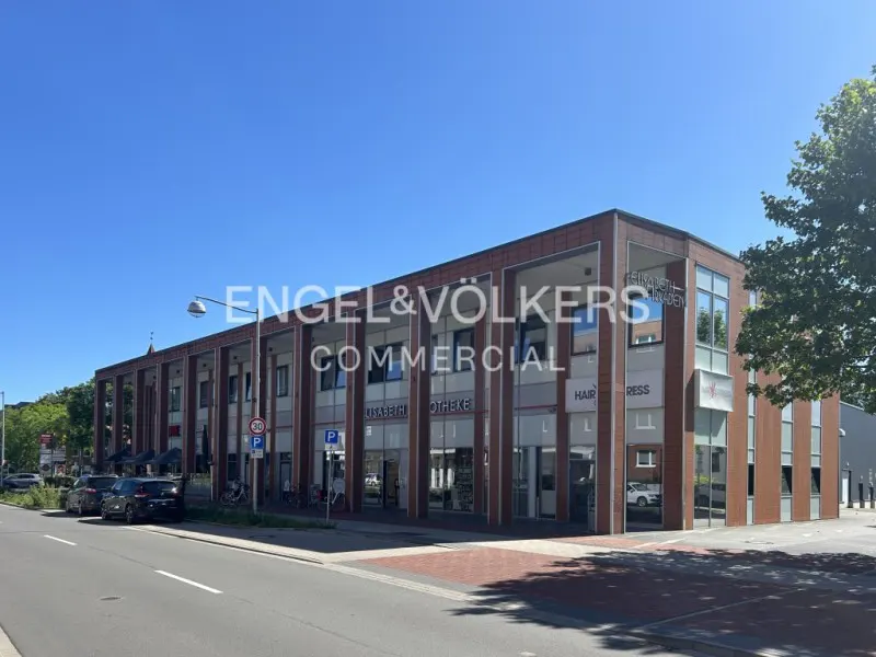 Exterior view of a commercial building with shops, parking, and the Engel & Völkers Commercial logo.