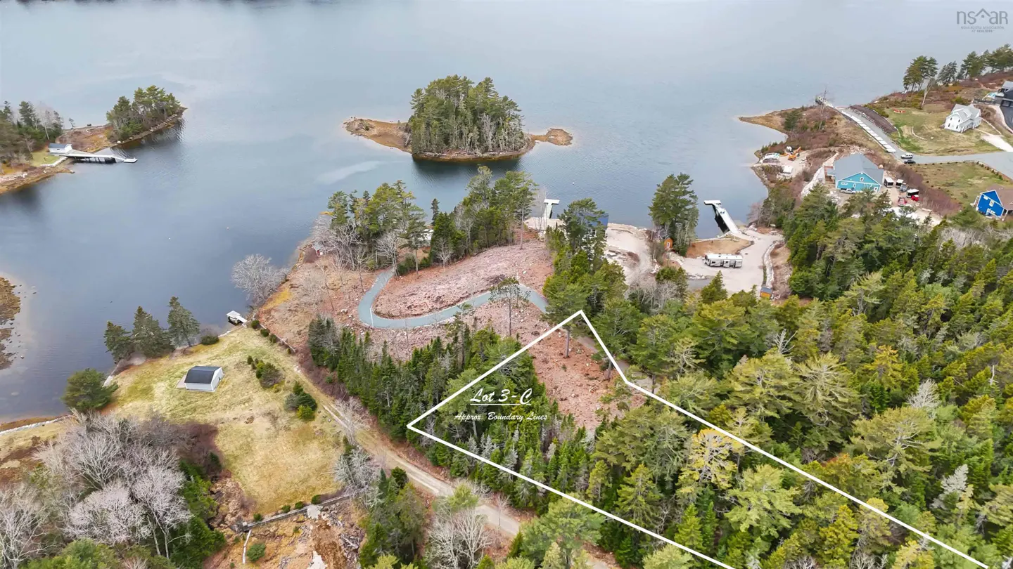 Aerial view of Lot 3-C, a wooded property outlined in white, near a lake with islands and waterfront homes.