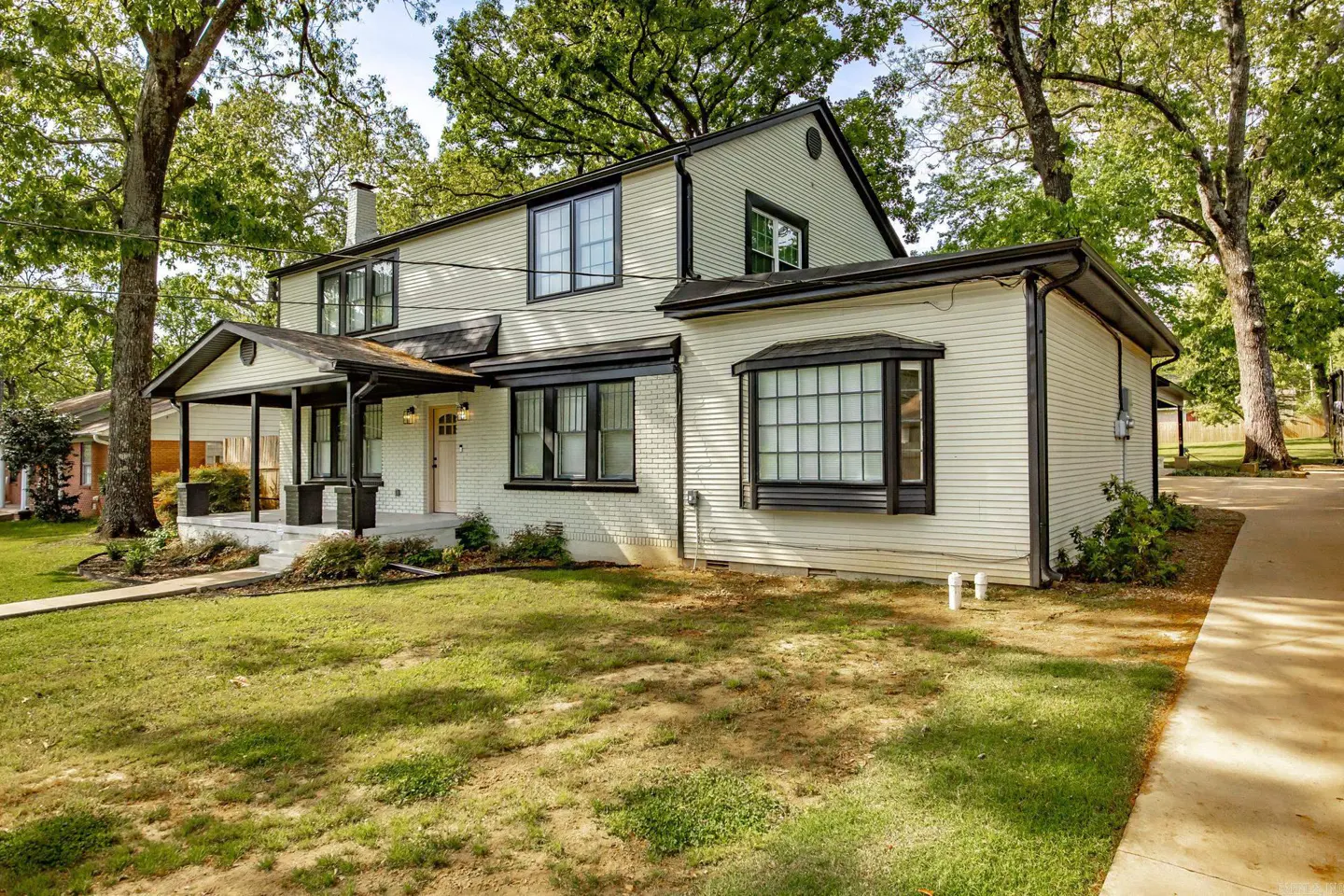 Two-story house with a porch, white siding, black trim, and green lawn.