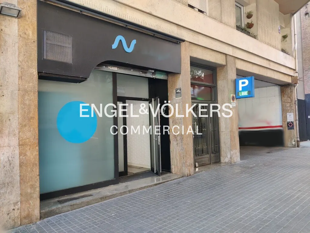 Engel & Völkers Commercial storefront with glass doors and windows. A blue parking sign is visible on the right.