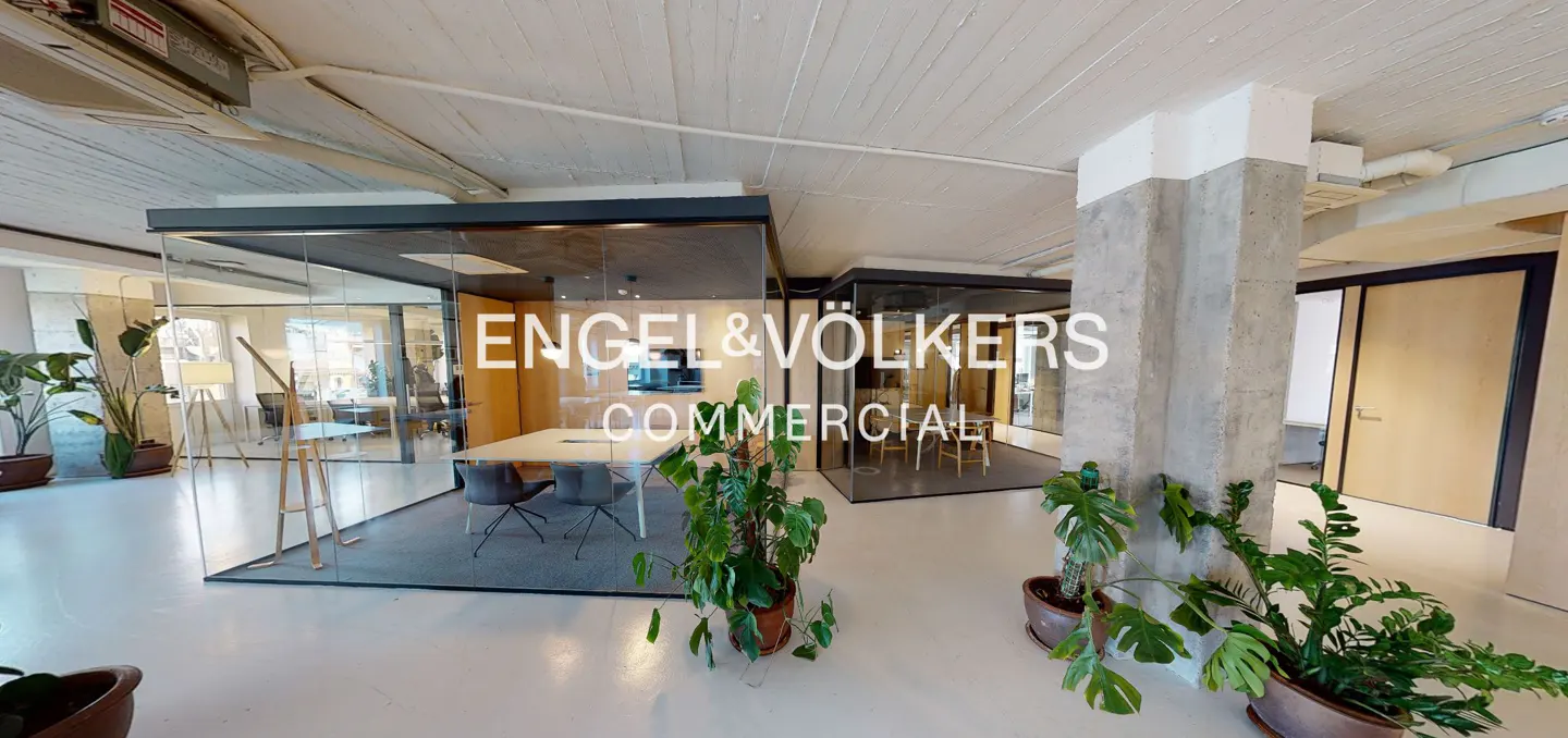 Engel & Völkers commercial office space with glass-walled conference rooms, potted plants, and concrete pillars.