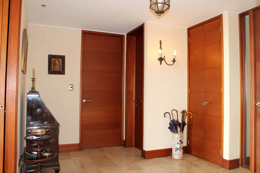 Entryway with beige walls, marble floors, and wood trim. A dark wood cabinet sits next to a door. An umbrella stand is next to a closet.