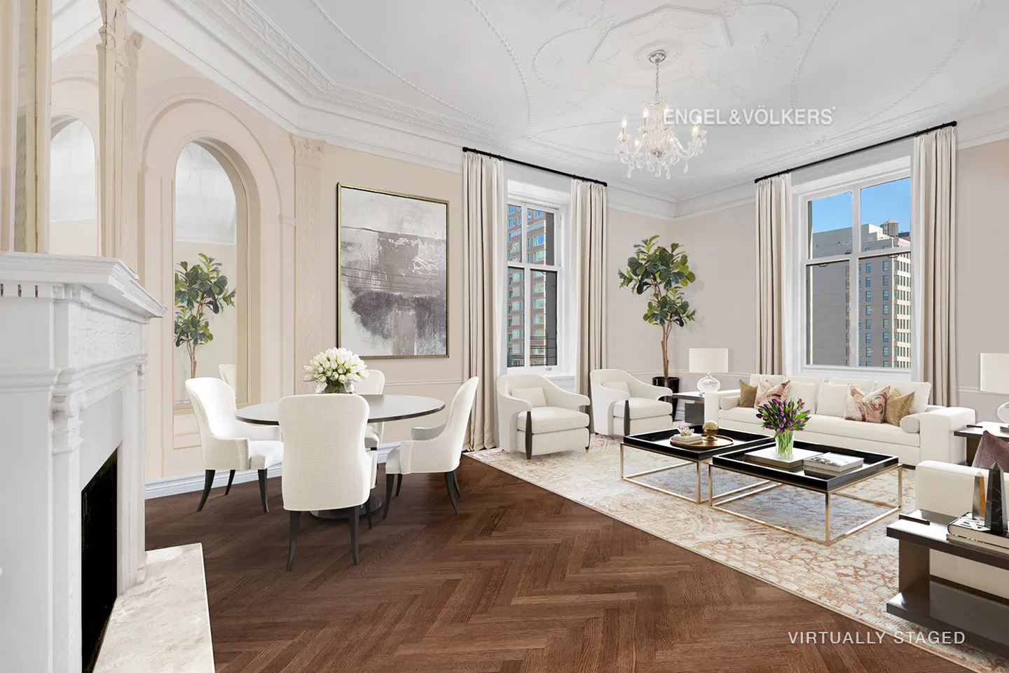 Bright, airy living room with white furniture, dark wood floors, and a chandelier. Large windows offer city views. "Virtually Staged" is watermarked.