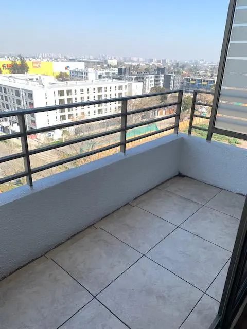 Balcony view with gray tiled floor, white wall, and black metal railing overlooking a cityscape under a clear blue sky.