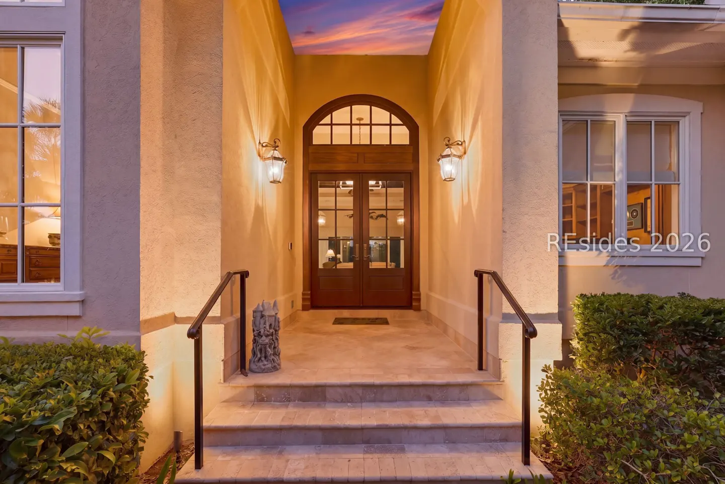 Exterior shot of a home's front entrance with a wooden door, stone steps, and warm lighting.