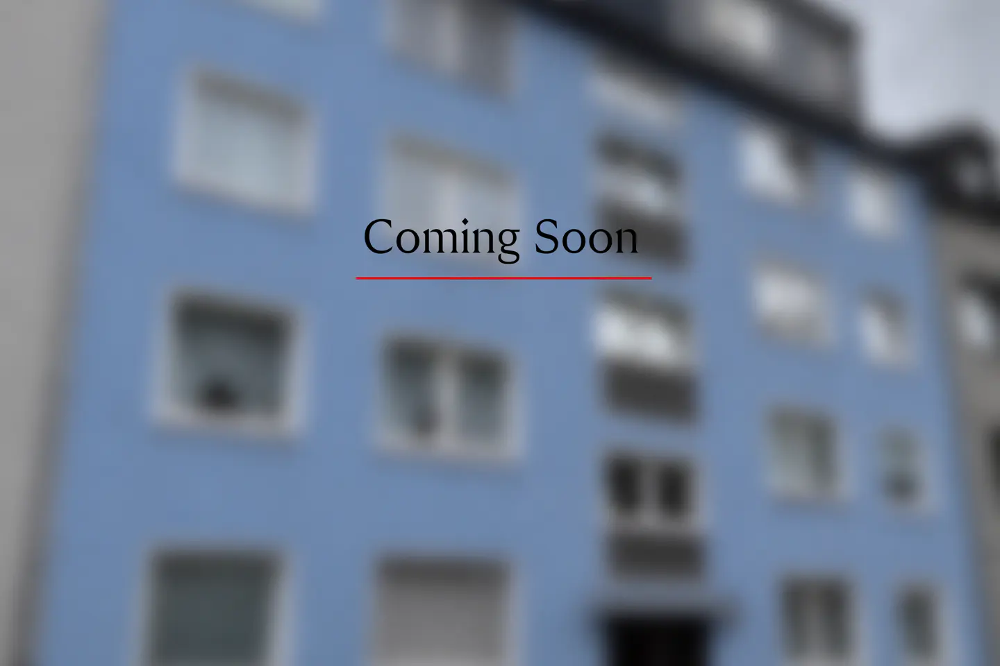Blurred image of a blue apartment building with white windows and the text "Coming Soon" in black with a red underline.