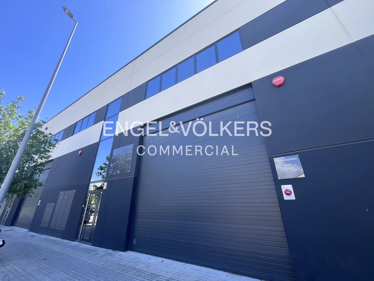 Exterior of a commercial building with the Engel & Völkers Commercial logo on a dark blue facade with white trim and blue windows.