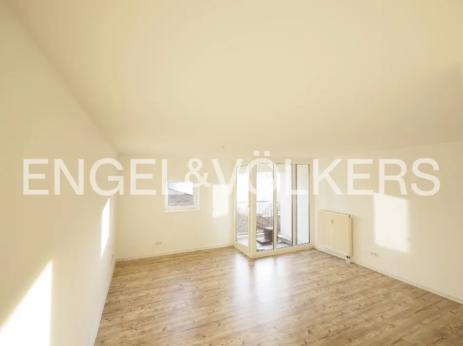 Empty room with light wood floors, beige walls, a small window, and a glass door leading to a balcony.