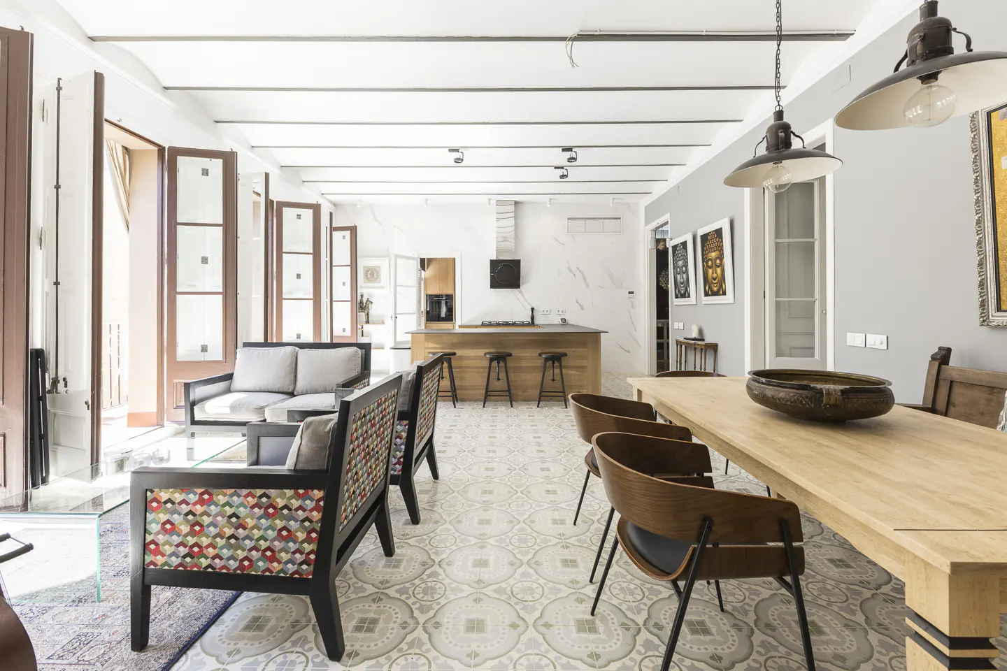 Open-concept living space with a kitchen island, dining table, and seating area. The floor is tiled with a gray and white pattern.