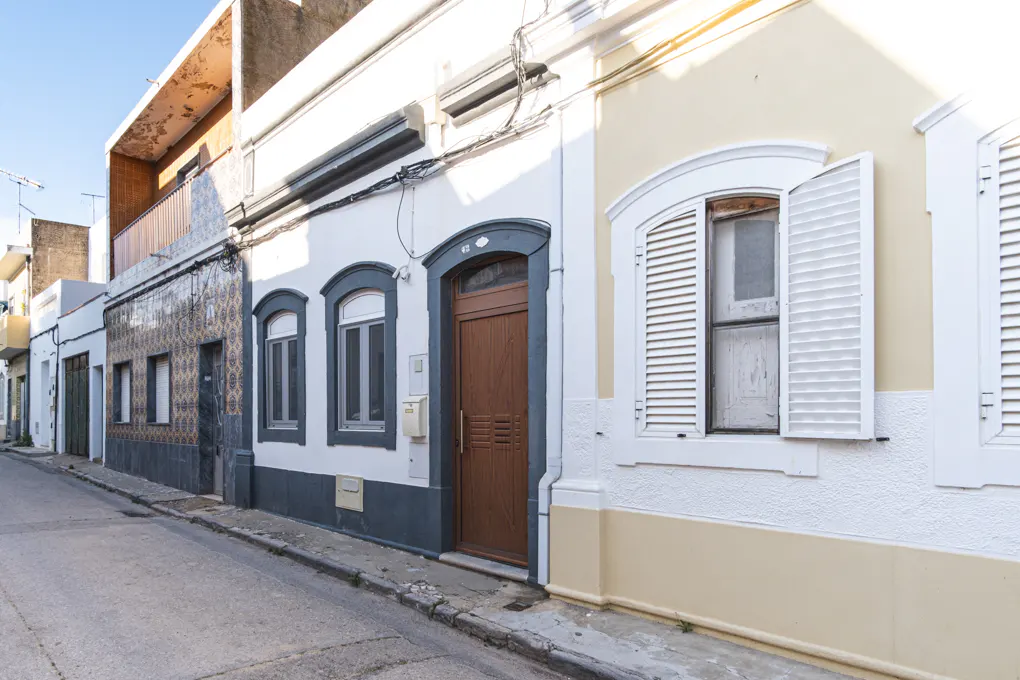 Street view of colorful houses with white and yellow facades, brown doors, and white window shutters.