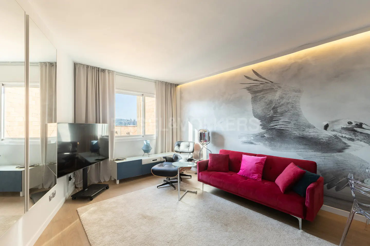 Living room with a red sofa, pillows, a black chair, and a large bird mural on the wall.
