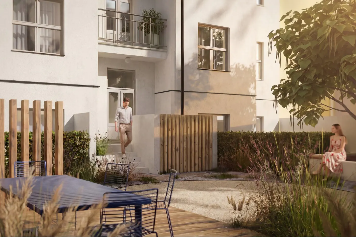 A man walks down steps of a white building into a courtyard with a blue table and chairs. A woman sits on a bench under a tree.