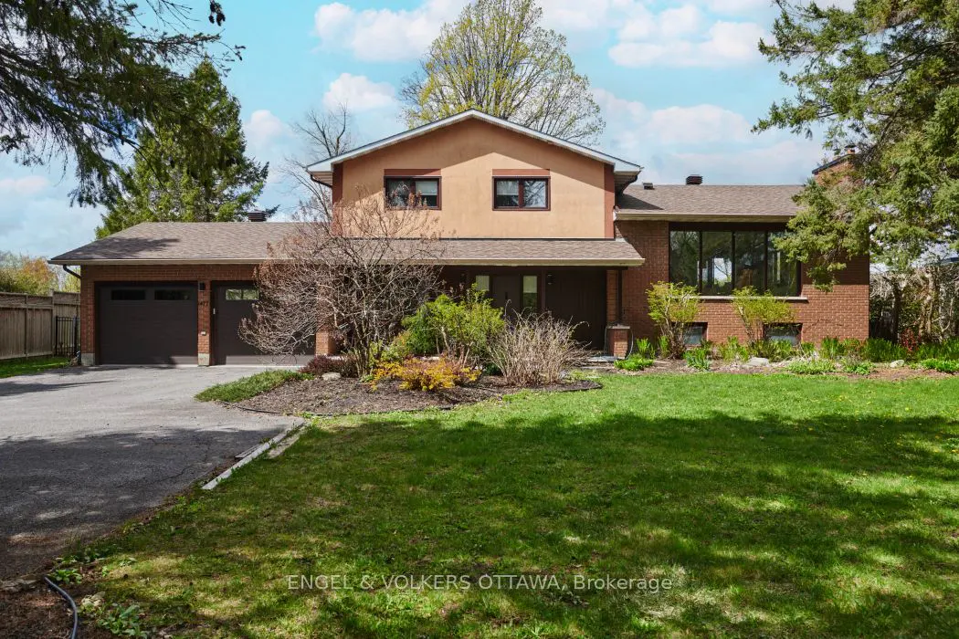 Two-story brick and stucco house with a green lawn, brown garage doors, and a blue sky.
